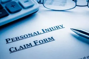 Personal injury claim form, a pen and glasses.